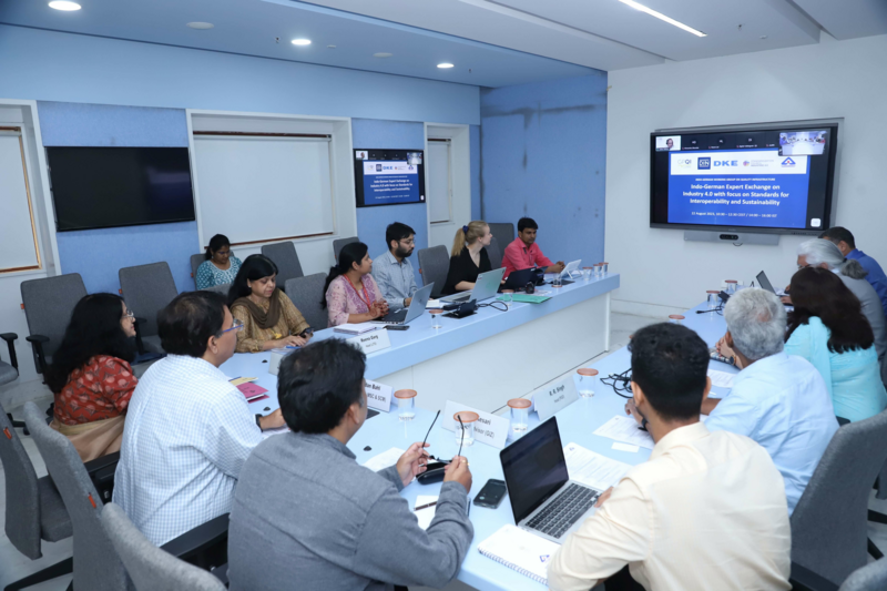 People sitting together at a conference table facing a screen with a presentation.