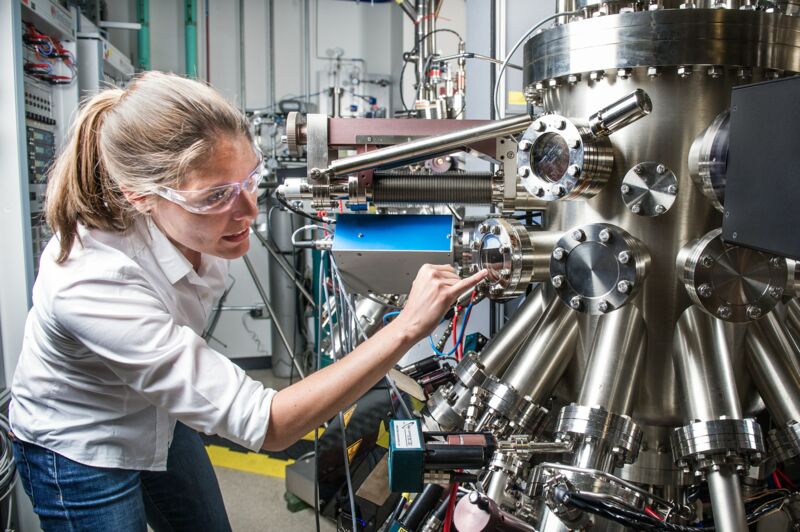 Frau mit Schutzbrille begutachtet große industrielle Maschine